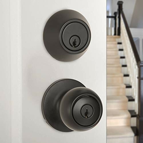 Black door knob and lock on white door with staircase in background.