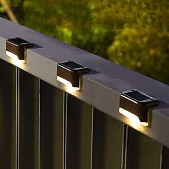 Four solar deck lights illuminating a railing at night.