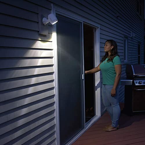 Woman standing by a sliding door illuminated by outdoor light.